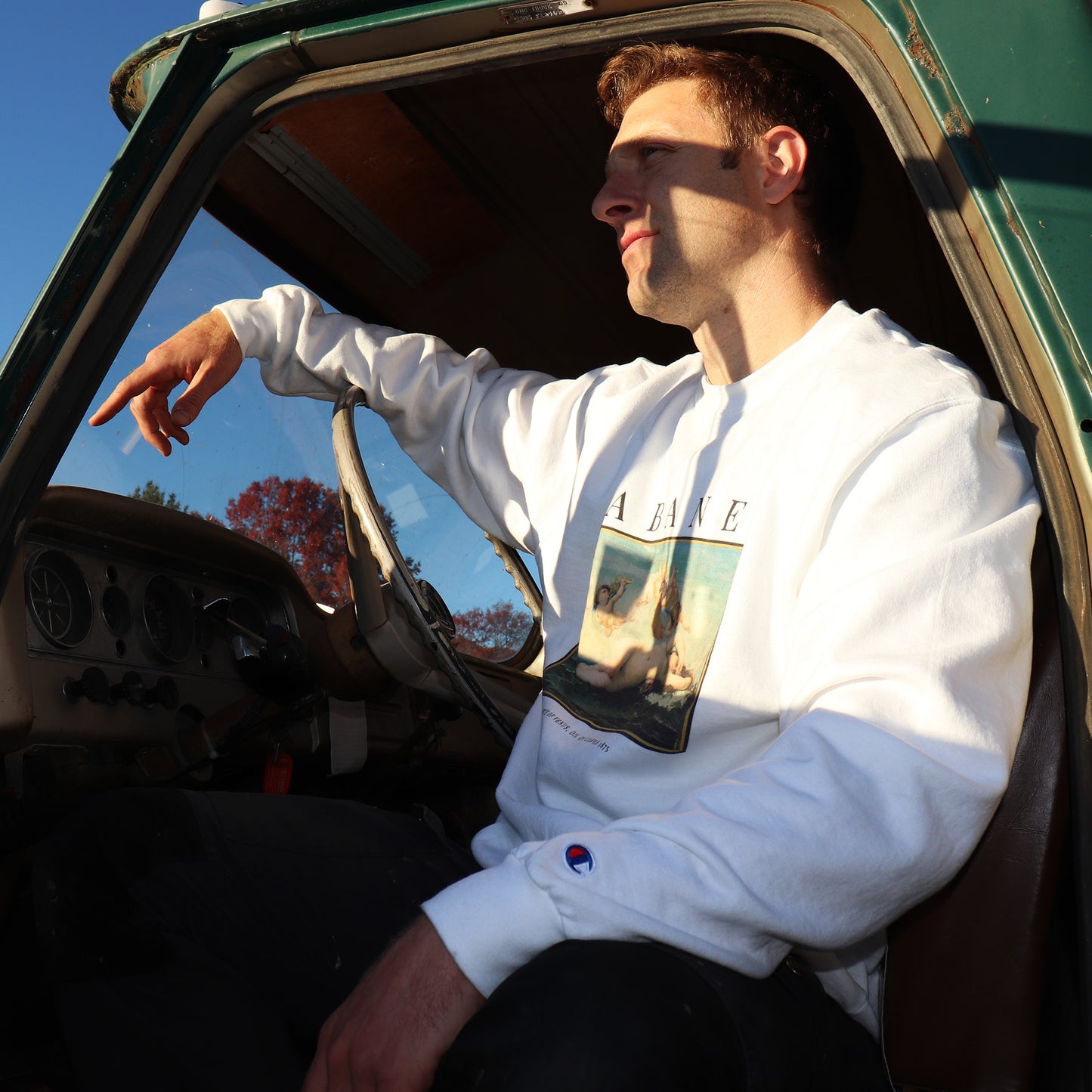 man in vintage truck wearing birth of venus sweatshirt at sunset. whitney baldwin home wearable art