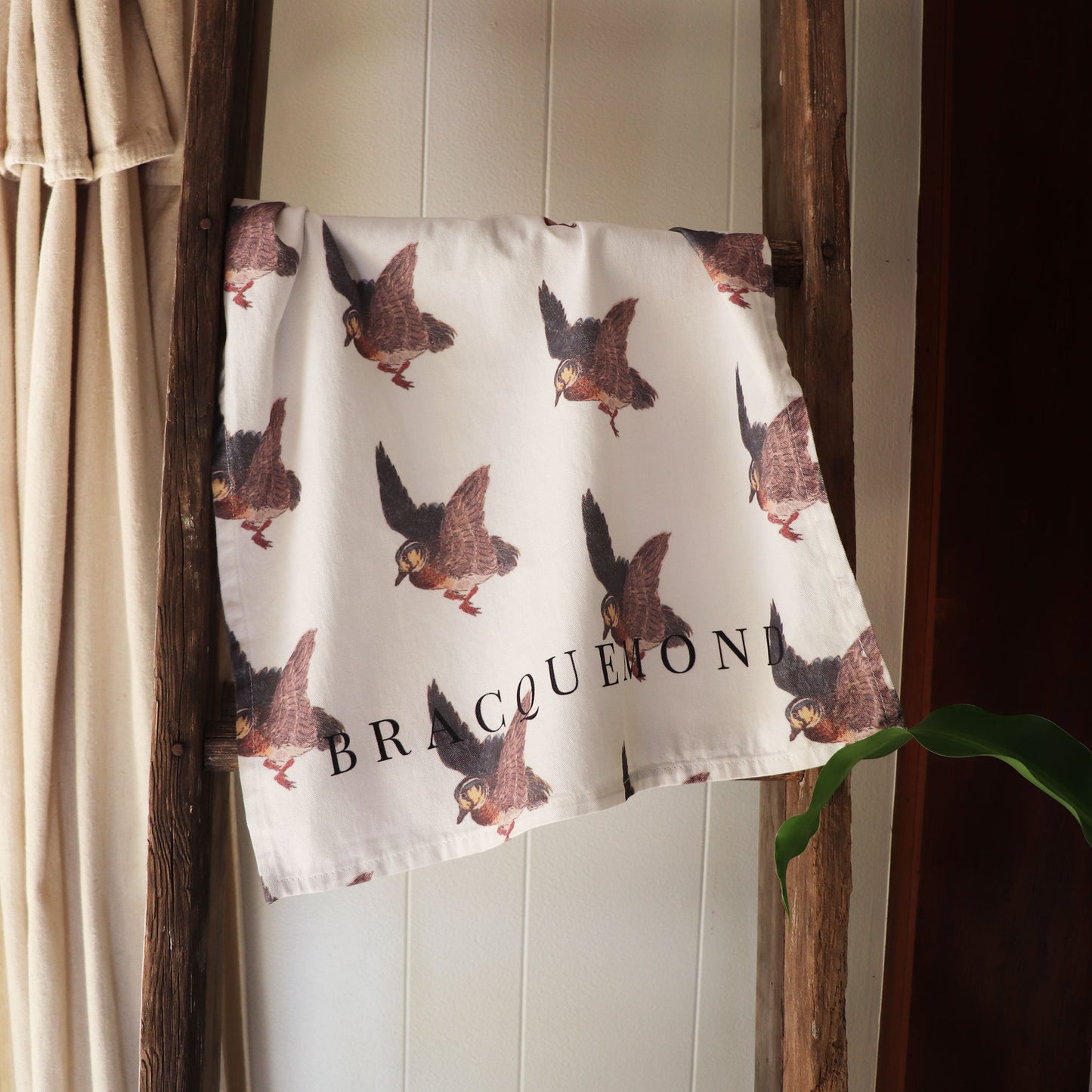 Bracquemond Duck Print Kitchen Towel. Repreating duck print on a soft kitchen towel. Towel is hung over wooden ladder