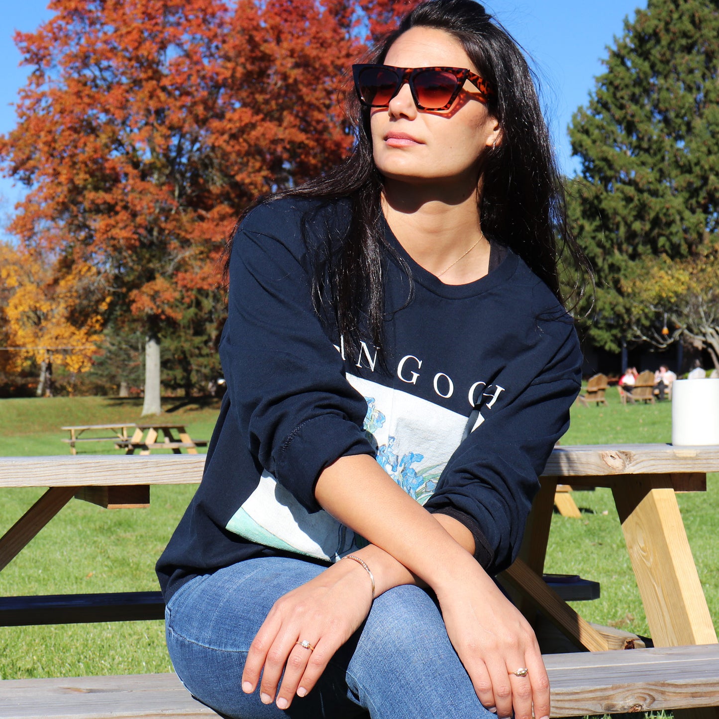 stylish woman wearing long sleeve navy vincent van gogh irises tshirt. sitting outside at a picnic table