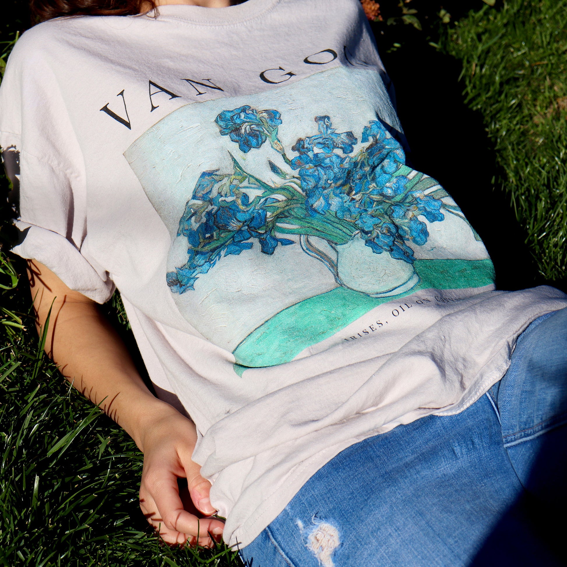 woman lying in grass wearing vincent van gogh irises tshirt in the color sand