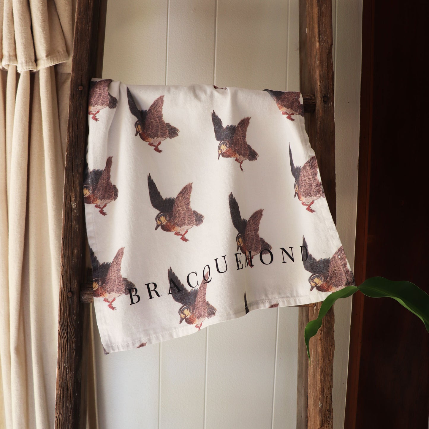 Bracquemond Duck Print Kitchen Towel. Repreating duck print on a soft kitchen towel. Towel is hung over wooden ladder 