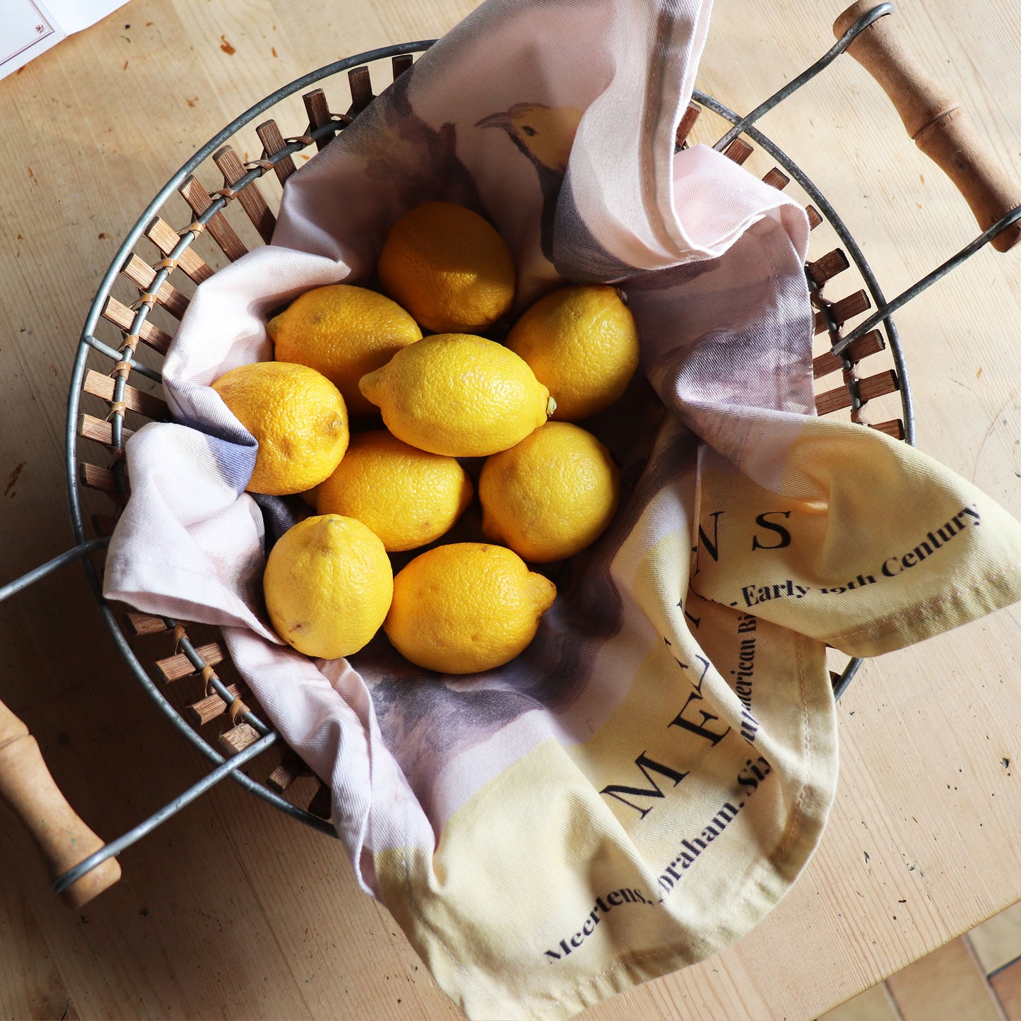 Abraham Meertens Six South American Birds painting on a kitchen towel. Inspired by the Metropolitan Museum Of Art. The kitchen towel is displaying in a fruit basket with lemons 